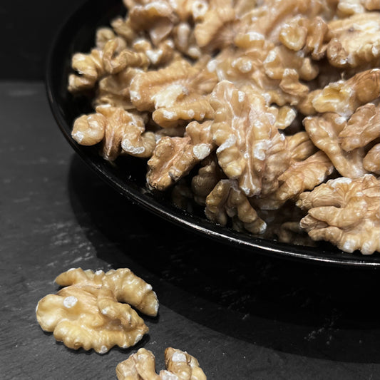 Heerlijke walnoten van Mijn winkel in een zwarte kom, perfect als snack of topping. Rijk van smaak en boordevol goede voedingsstoffen.