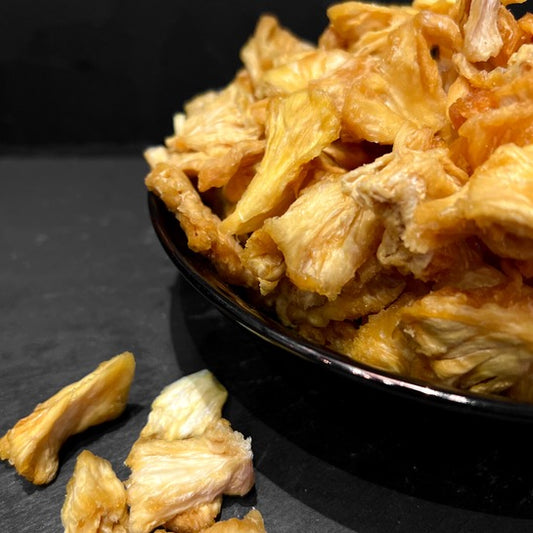 Gedroogde ananas van Mijn winkel, heerlijke gezonde snack in een zwarte kom, perfect voor tropische gerechten of als tussendoortje.