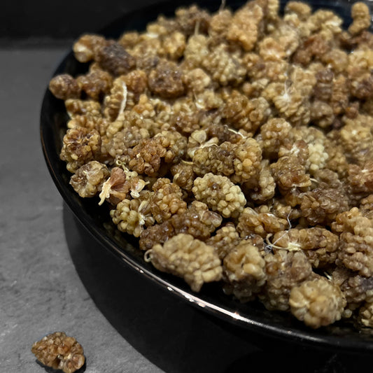 Gele mulberries in een zwarte kom van Mijn winkel, perfect voor snacken, met de titel Moerbei.