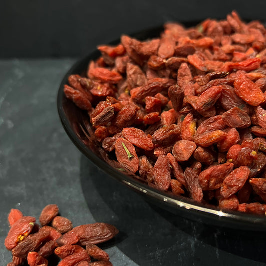 Goji bessen in een zwarte kom van Mijn winkel, rijke, gedroogde bessen met een dieprode kleur.