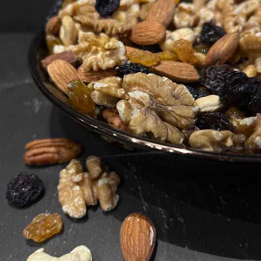 Een mix van noten en gedroogd fruit in een zwarte schaal, perfecte gezonde snack van Mijn winkel - Studentenhaver.