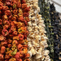 Een kleurrijke rij gedroogde paprika's van Mijn winkel, met een mix van rode, groene en zwarte variëteiten, perfect voor het toevoegen van rijke, intense smaak aan gerechten. Gedroogde Paprika voor een volle, rokerige smaak met een vleugje zoetheid.