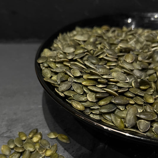 Gepelde pompoenpitten van Mijn winkel, prachtig gestapeld in een diep zwart bord, perfect voor snacking of als gezonde topping.