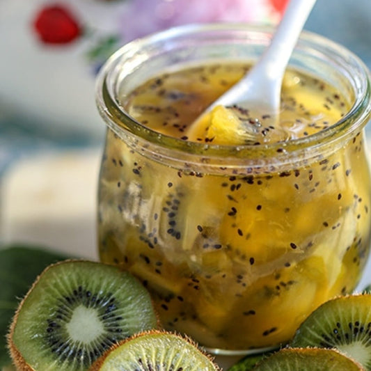 Een borrelend potje Kiwi Jam van Mijn winkel 750g, gevuld met sappige stukjes kiwi, omringd door verse kiwi's. Perfect om te genieten van de frisse en fruitige smaak!
