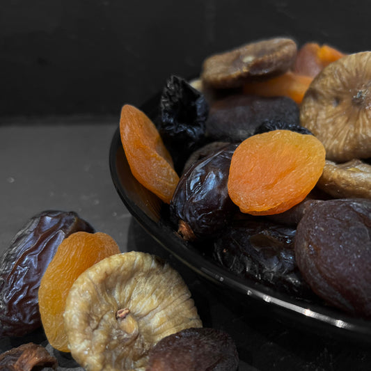 Een mooie schotel gevuld met de Fruitmix Zilver van Mijn winkel, bestaande uit een kleurrijke mix van gedroogde vruchten zoals abrikozen, vijgen en dadels. Perfect als gezonde snack!