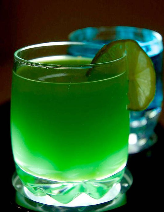 Verfrissende limoensiroop van Mijn winkel, perfect voor dorstlessende dranken en cocktails, geserveerd in een helder groen glas met schijfje limoen.