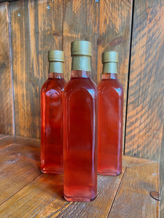 Drie flessen Druivenazijn van Mijn winkel, met een zachte, fruitige kleur, perfect voor dressings en marinades.