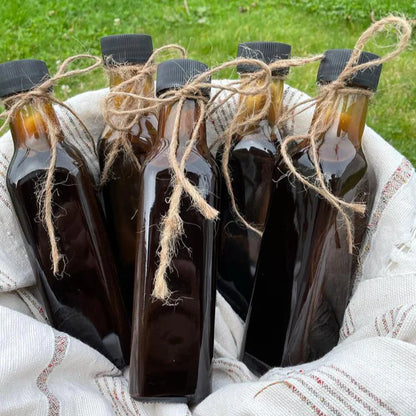 Handgemaakt biologisch granaatappelmelasse van Mijn winkel, gepresenteerd in glazen flessen met een natuurlijk touwtje, perfect voor gebruik in dressings en desserts.