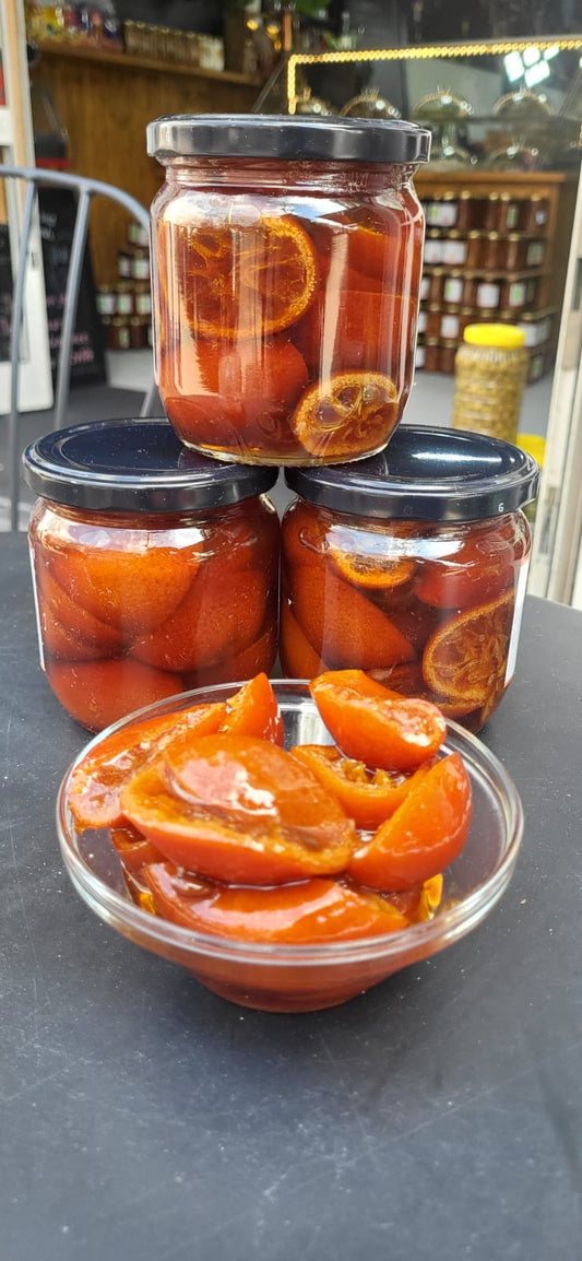 Drie potten MandarijnenJam van Mijn winkel, gevuld met sappige mandarijnen op een zwarte tafel, samen met een glazen schaal vol gesneden mandarijnen, ideaal voor een heerlijke snack.
