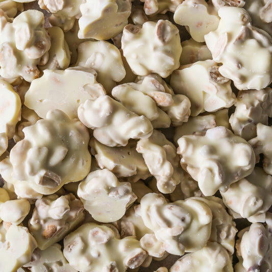 Close-up beeld van Pindarotsjes Wit van Mijn winkel, knapperige pinda's omhuld met romige witte chocolade, perfect voor een verwenmoment.