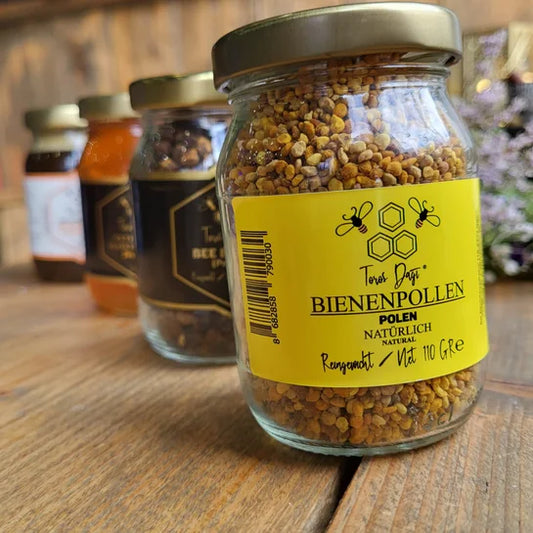 Een glazen pot met bijenpollen van Mijn winkel, perfect voor een natuurlijke energieboost. De pot heeft een gele label en staat tussen andere producten.